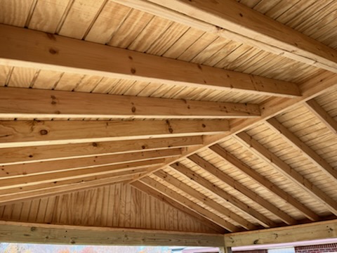 "Interior view of a wooden ceiling with exposed beams and a sloped design."
