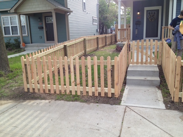 "Residential front yard featuring a newly installed wooden picket fence and concrete pathway."