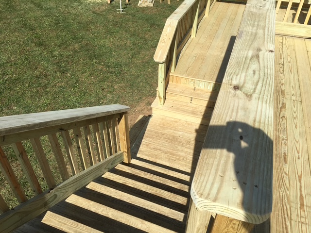 "Bird's-eye view of a wooden deck with stairs leading down to a grassy area."