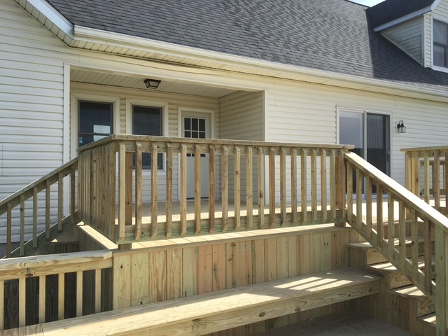 Wooden ramp leading to a white house with multiple doors and windows.